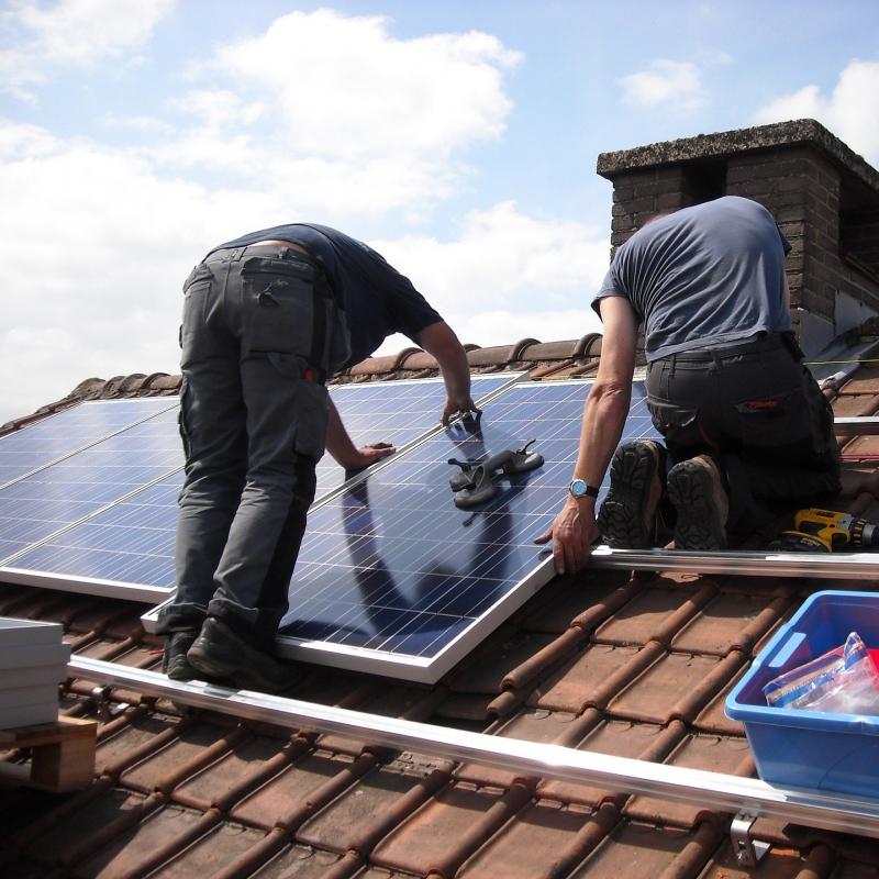 Twee mannen monteren zonnepanelen op een dak